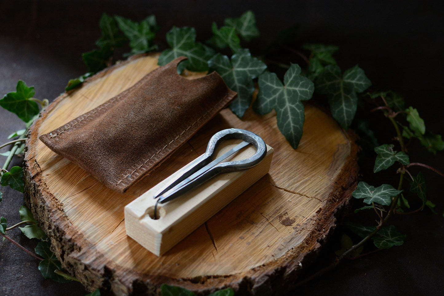 Guimbarde artisanale avec gravures primitives posée sur son support en bois et accompagnée de son pochon en daim