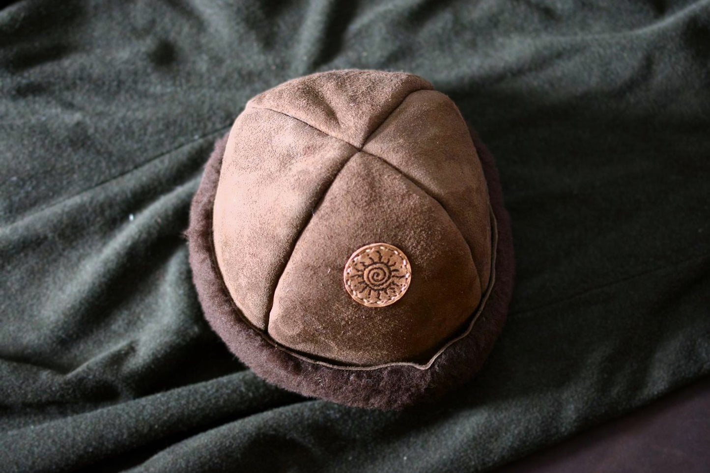 Vue de dessus du bonnet shearling mouton, détail des coutures artisanales et patch soleil