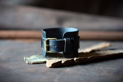 "Bracelet de force en cuir noir — vue boucle ardillon laiton apparente"