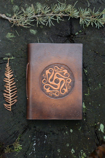 Carnet en cuir tannage végétal motif celte ancien vu de face posé sur une souche de bois - Amrod & Gardarson