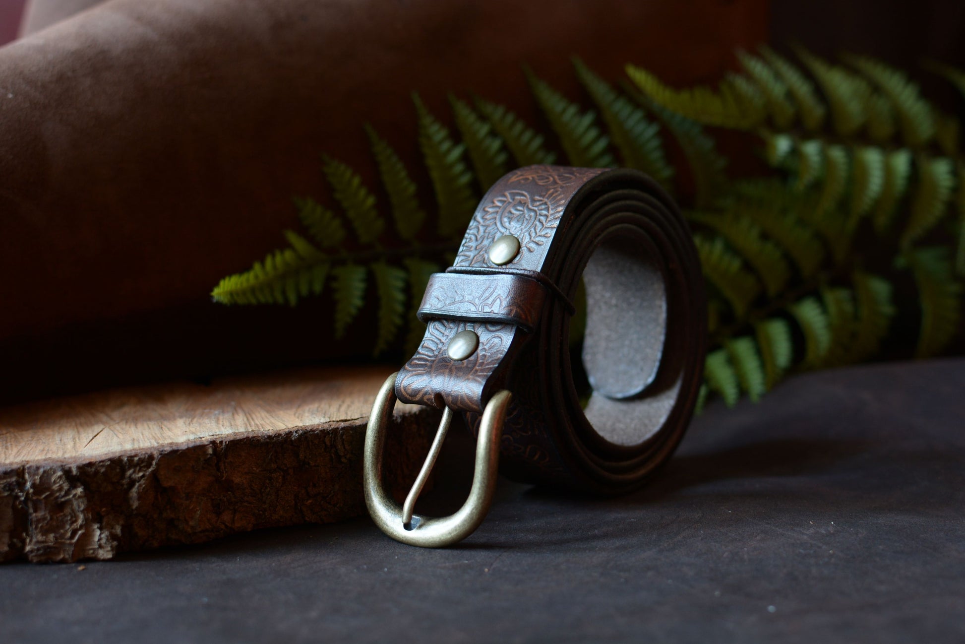 Ceinture batik marron en cuir tannage végétal roulée, décor studio fougère et rondin de bois – Amrod & Gardarson