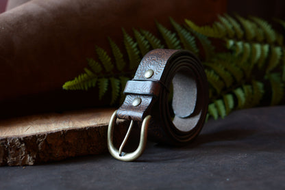Ceinture batik marron en cuir tannage végétal roulée, décor studio fougère et rondin de bois – Amrod & Gardarson