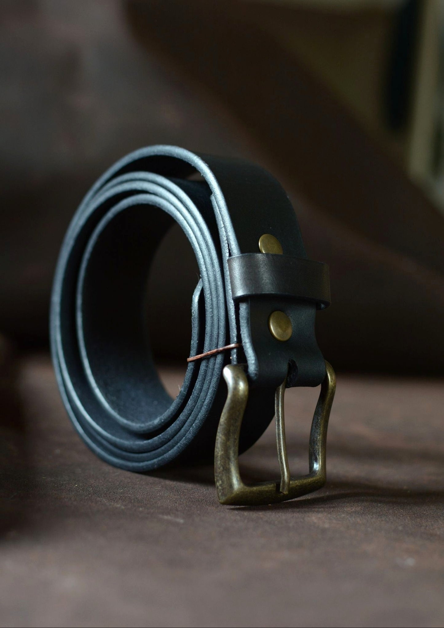 Ceinture cuir tannage végétal noire roulée de profil – boucle rectangle laiton – Amrod & Gardarson
