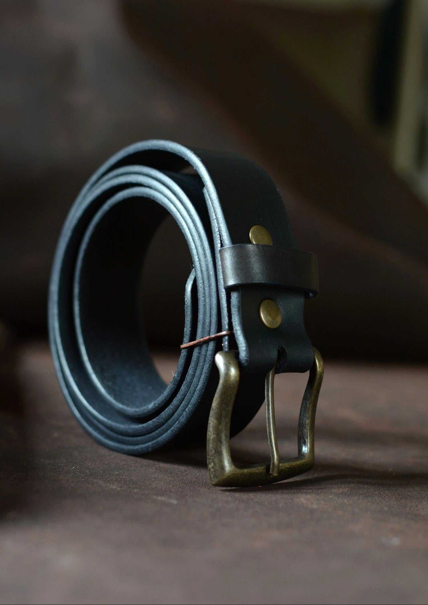 Ceinture cuir tannage végétal noire roulée de profil – boucle rectangle laiton – Amrod & Gardarson