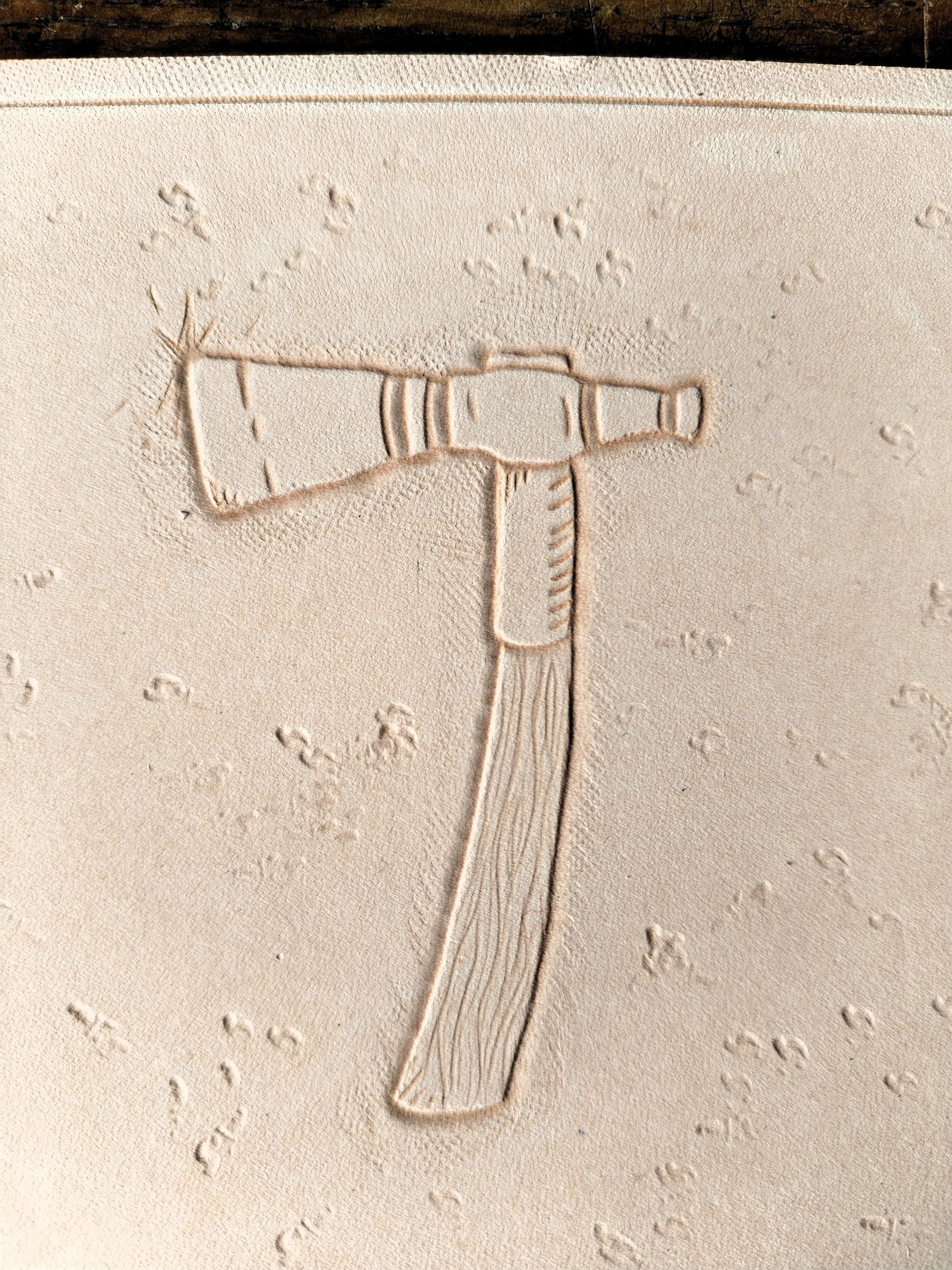 Repoussage à la main du motif tomahawk sur cuir tannage végétal - savoir-faire artisanal Atelier d'Amrod