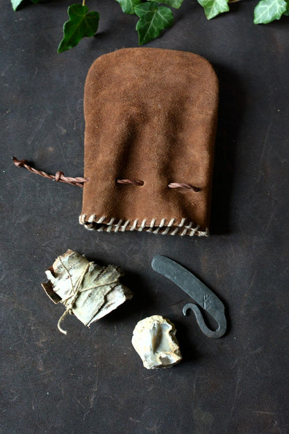 Kit allume-feu traditionnel n°2 avec bourse en cuir ouverte présentant le briquet, le silex et l'écorce de bouleau