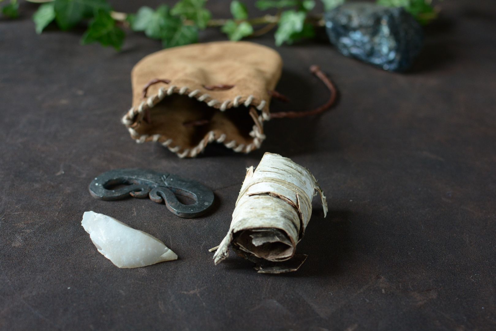 Kit allume-feu traditionnel avec bourse en cuir ouverte présentant le briquet, le silex et l'écorce de bouleau